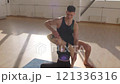 Fitness trainer practicing yoga with a young woman apprentice on yoga mats in the gym in the morning, fitness girl Generation Z and trainer man yoga workout in light fitness room 4K UHD B-Roll footage 121336316