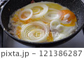 Frying eggs with slices of white onion on frying pan 121386287