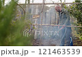 A Gardener Actively Working in Nature Surrounded by Beautiful Smoke Effects in the Air 121463539