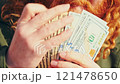 A close-up of hands holding a fan of dollar bills. The person licks their lips, showing greed and obsession with money. Concept of financial dependency, wealth addiction, and desire to get rich 121478650