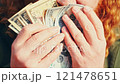 Close-up of hands holding a fan of dollar bills against a bright background. A symbol of financial growth, success, and achieving wealth. Ideal for business, investments, and prosperity concepts 121478651