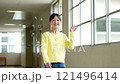 Elementary school girl waving to her friends in the school hallway 121496414