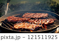 Three pieces of meat are being grilled on a grill 121511925