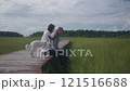 Men, women and dog relaxing on a wooden path in the swamp  121516688