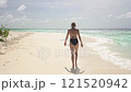 A young woman in a swimsuit walks along a sandy seashore on an uninhabited island 121520942