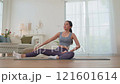 Young Asian woman in sportswear doing yoga in her home or house for health, sports and wellness, Enjoying Domestic Fitness Training And Healthy Lifestyle, Dressed In Stylish Sportswear And Smiling 121601614