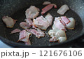 Pieces of bacon are fried in a non-stick frying pan 121676106