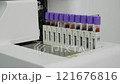 Test tubes with liquids of different colors go inside laboratory device. Equipment with multiple sample vials arranged for analysis in a healthcare setting 121676816