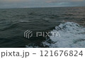 Sea. Splashes of waves fly by. View to waves low on water. Wind breaks waves with splashes. White foam on wind. Side view along ship. 121676824