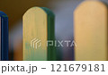 The colorful painted wooden boards on the fence around a playground are illuminated by the rays of the setting sun. Pula, Croatia - January 3, 2025 121679181