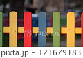 The colorful painted wooden boards on the fence around a playground are illuminated by the rays of the setting sun. Pula, Croatia - January 3, 2025 121679183