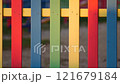 The colorful painted wooden boards on the fence around a playground are illuminated by the rays of the setting sun. Pula, Croatia - January 3, 2025 121679184