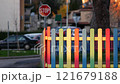 The colorful painted wooden boards on the fence around a playground are illuminated by the rays of the setting sun. Pula, Croatia - January 3, 2025 121679188