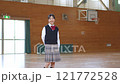 A female student standing and smiling in a gym 121772528
