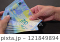 White Woman Counting 20 Euro Banknotes on Black Table 121849894