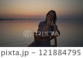 Woman Posing Gracefully on Chair at Sunset 121884795