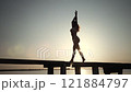 Woman Walking Gracefully on a Pier at Sunset 121884797