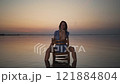 Woman Sitting Confidently on Chair in Sunset Waters 121884804