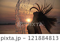 Woman Flipping Hair in Sunset Splash 121884813