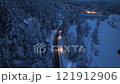Aerial view of mountain road in forest during snowfall at night 121912906