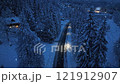 Aerial view of mountain road in forest during snowfall at night 121912907