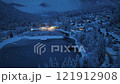Aerial view of forest during snowfall, lake and house at night 121912908