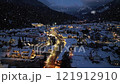 Aerial view of mountain village in snowfall, city lights at night 121912910