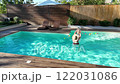 Mother playing with baby in outdoor swimming pool surrounded by nature on a sunny day 122031086