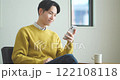 Young man sitting on a sofa and using a smartphone 122108118