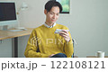 A young man sitting on a sofa and watching a video on his smartphone 122108121