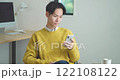 Young man sitting on a sofa and using a smartphone 122108122