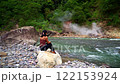 Asian girl sitting on a rock on the bank of a strong mountain river looking at geothermal spring and green jungle 122153924