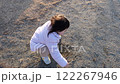 女の子が木の棒で地面に落書きをして遊ぶ姿 122267946
