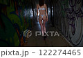 back view of woman wearing lingerie walking down narrow corridor in abandoned building 122274465