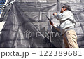 戸建て家屋の外壁修繕工事進行状況を確認する男性 122389681