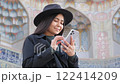 A young woman uses her smartphone to stay connected, messaging and browsing social networks. A seamless blend of modern technology, style, and digital lifestyle. 122414209