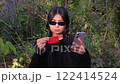 Sitting outdoors woman uses her mobile phone for a secure online payment, blending technology with a peaceful setting.  122414524