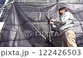戸建て家屋の外壁修繕工事進行状況を確認する男性 122426503