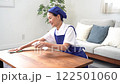 青色のエプロンを付けた白いポロシャツのシニアのハウスキーパー 122501060