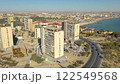 AKTAU, KAZAKHSTAN - FEBRUARY 1, 2025: Waterfront view of modern buildings and coastal area with busy street and clear blue sky 122549568