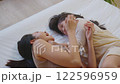 Beautiful and tender moment featuring Asian mother lying on bed with her daughter. They are smiling and looking at each other capturing warm and joyful connection 122596959
