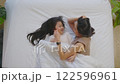 Beautiful and tender moment featuring Asian mother lying on bed with her daughter. They are smiling and looking at each other capturing warm and joyful connection 122596961