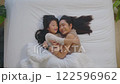 Beautiful and tender moment featuring Asian mother lying on bed with her daughter. They are smiling and looking at each other capturing warm and joyful connection 122596962