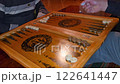A close-up of a backgammon game in progress shows players moving black and white pieces on a wooden board, capturing the intensity and strategy of the game play 122641447
