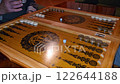 A close-up of a backgammon game in progress shows players moving black and white pieces on a wooden board, capturing the intensity and strategy of the game play 122644188