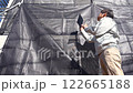 戸建て家屋の外壁修繕工事進行状況を確認する男性 122665188