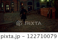 Historical reenactor walking on cobblestone street at night 122710079