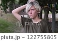 Pensive Teen with Blonde Hair Outdoors, Playful Expression 122755805
