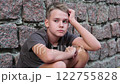Sad depressed teenage boy alone near stone wall outside, feeling angry and lonely 122755828