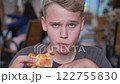 Teenager happily eats pizza and dances while looking at camera in cafe. Close up of teenage boy's face 122755830